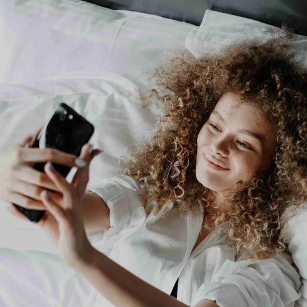 Mujer haciéndose una selfie en la cama