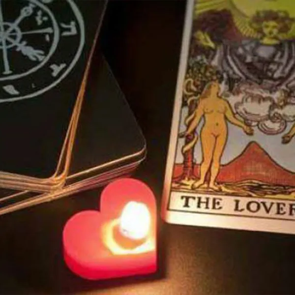 Cartas del Tarot junto a una vela roja, encendida, en forma de corazón