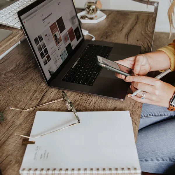 Mujer joven estudiando virtualmente desde su portátil y teléfono móvil