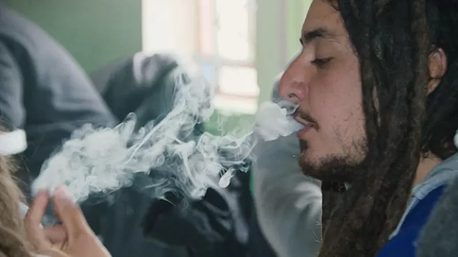 Hombre con dreadlocks fumando marihuana