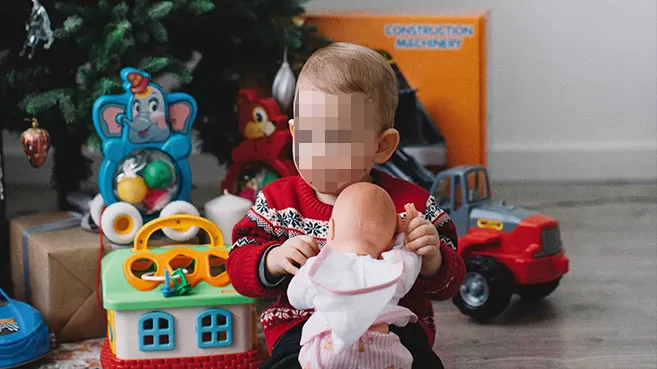 Niño recibiendo regalos debajo del árbol de Navidad