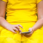 Niña usando un smartphone sentada en un columpio